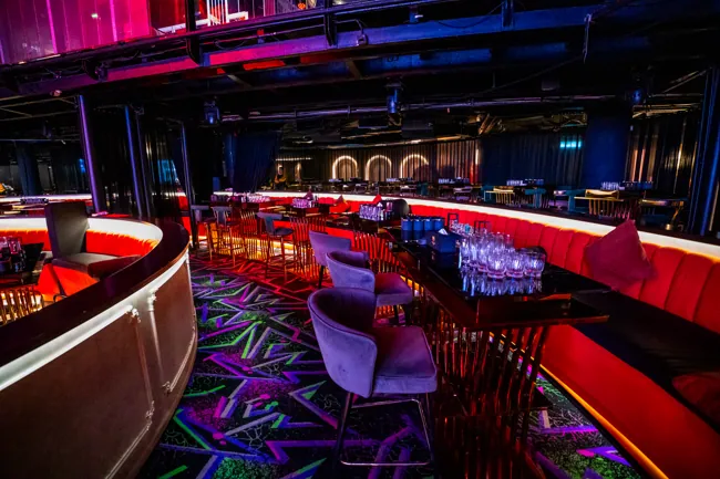 Curved red lounge seating with patterned floor and stage beyond at Millennium Club KL, Bukit Bintang