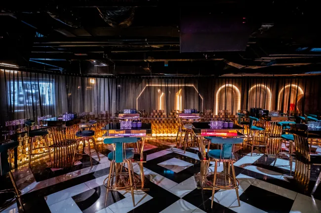 Tables and chairs beneath gold geometric wall arches at Millennium Club KL, Bukit Bintang